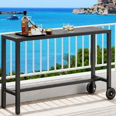 an outdoor table with drinks on it next to the ocean