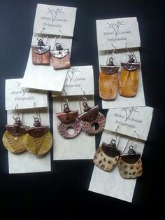 six pairs of earrings are on display in front of some white paper and black background