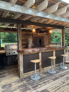 an outdoor bar with three stools and a grill in the back ground, surrounded by wood plank flooring