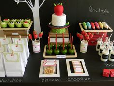 an assortment of desserts and snacks are displayed on a black table with white paper bags