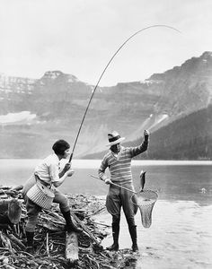 an old photo of two people fishing in the water