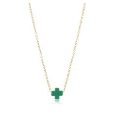 a green cross necklace on a gold chain