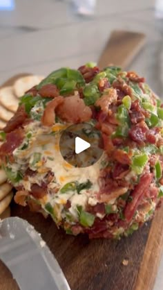 an appetizer with bacon, cheese and vegetables is on a cutting board next to crackers