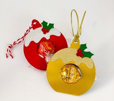 an ornament is hanging from a christmas tree with candy in the shape of a bell