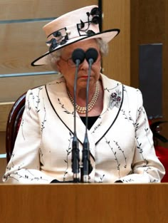 an older woman wearing a white hat and holding a microphone