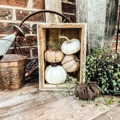 some white pumpkins are in a wooden box