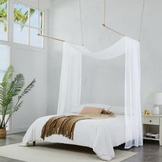 a white bed sitting in a bedroom on top of a hard wood floor next to a window