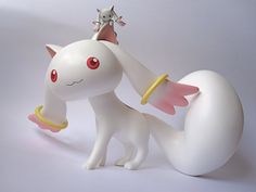 a white cat figurine with red eyes and wings on it's back