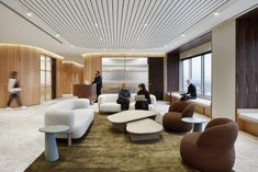 people are sitting in the waiting area of an office with modern furniture and wood paneling