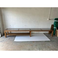 a wooden bench sitting on top of a white rug next to a green chair and table