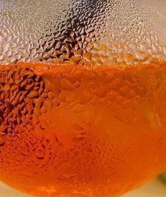 an orange is sitting on top of a table with water droplets all over the surface