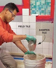 a man in an orange shirt and green gloves is pouring cement into a pail