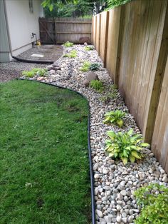 a garden with rocks and grass next to a fence