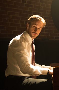 a man sitting at a piano in front of a stained glass window