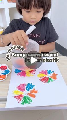 a little boy is painting with watercolors on the paper and then using a brush