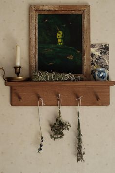 there is a painting on the wall and some flowers hanging from it's shelf