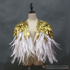 a mannequin with white and gold feathers on it's torso, standing in front of a gray background