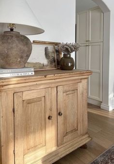 a wooden cabinet sitting in the middle of a living room with a lamp on top of it