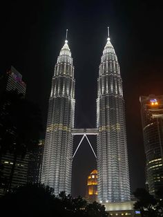 two tall buildings lit up at night in the middle of a large body of water