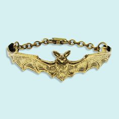 Antique gold bat wraps around your wrist with the help of a patterned antique gold plated chain. Metal: 14kt gold plate over brass on bat, 24kt gold over brass on chain, aged brass clasp Size: 7.5" Overall Foldover Clasp Made in the USA Slytherin Jewelry, Gold Compass Necklace, Knife Necklace, Dark Decor, Fun Bracelet, Neck Accessories, Compass Necklace, Buckle Bracelet, Halloween 2024