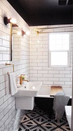 a bathroom with black and white tiles on the floor, sink, mirror and bathtub