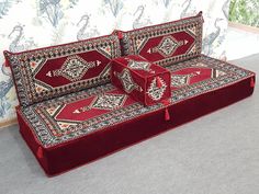 a red couch sitting on top of a carpet covered floor