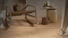 a rocking chair next to a table with a vase on it and a book in the background