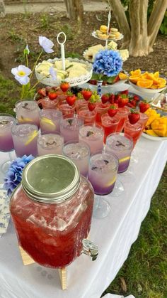 a table topped with lots of glasses filled with liquid and fruit on top of it