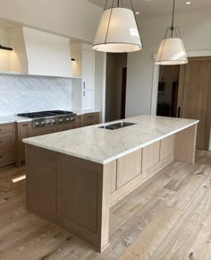 a large kitchen with an island and two pendant lights