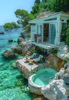 an outdoor hot tub in the middle of some clear blue water with two chaise lounges next to it