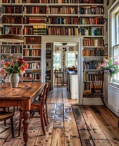 a room filled with lots of books on top of a wooden floor next to a window