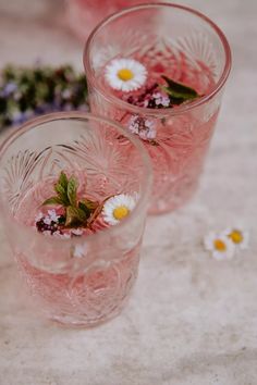 three glasses with flowers in them sitting on a table