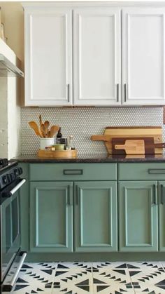 a kitchen with green cabinets and black stove top in the center, white cupboards on both sides