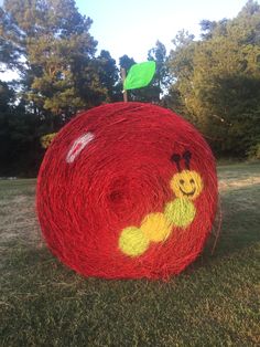 a red ball with a smiling face drawn on it and a green leaf sticking out of the top