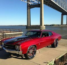 a red and black car parked under a bridge