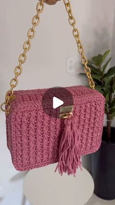 a pink purse with a gold chain hanging from it's shoulder and a video playing on the screen