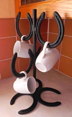 three cups are hanging from a black and white holder