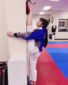 a woman leaning against a wall while holding onto a piece of luggage