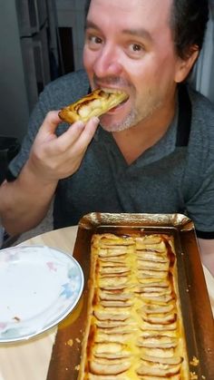 a man sitting at a table with a pan of food in front of his face