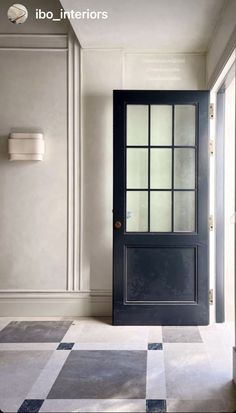 an empty room with a black door and checkered flooring on the floor is shown