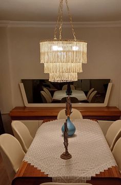 a chandelier hanging over a dining room table with chairs and a mirror in the background