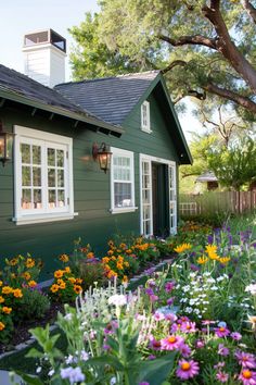 a green house with lots of flowers in the front yard