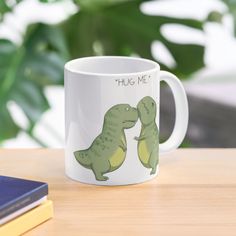 a coffee mug with two dinosaurs kissing on it's side and the words hug me written in large letters