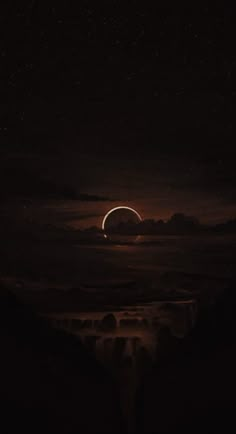 an eclipse in the night sky with clouds and stars above it, as seen from a distance