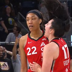 two women in red uniforms standing next to each other on a court with people watching