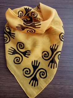 a yellow bandana with black designs on it sitting on top of a wooden table