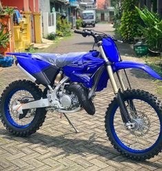 a blue dirt bike parked on top of a brick road