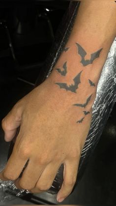 a person's hand with a tattoo on it that has bats all over it