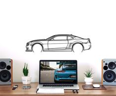 a laptop computer sitting on top of a desk next to speakers and a wall mounted car