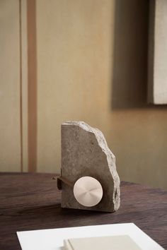 a rock sitting on top of a wooden table next to a paper towel dispenser